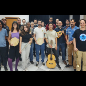 Grupo de Choro do Cefart é composto por dezoito pessoas, sendo duas mulheres. O grupo está junto, sorridente. Algumas pessoas seguram instrumentos